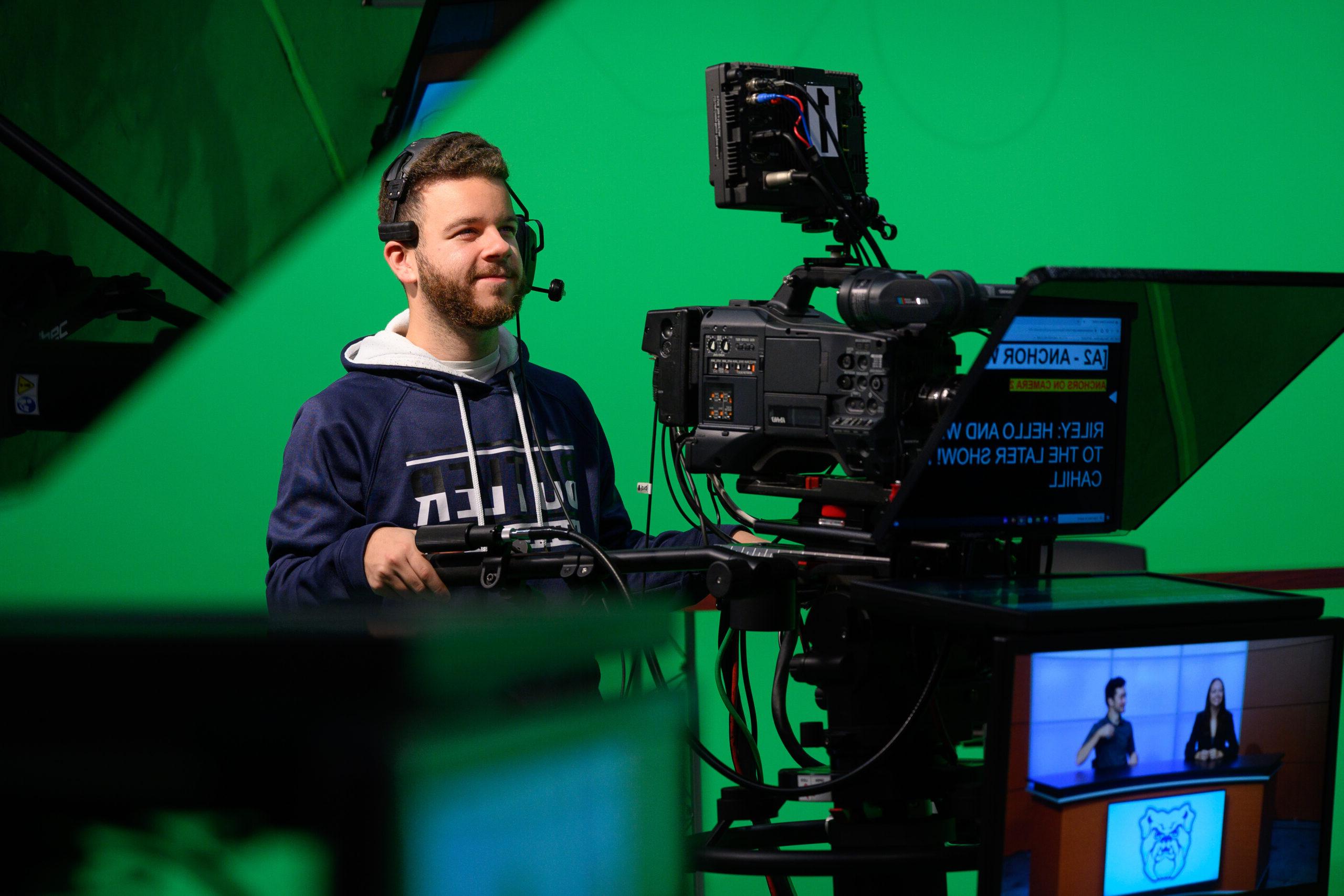 Male 皇冠投注 student working a production camera during TV shoot.